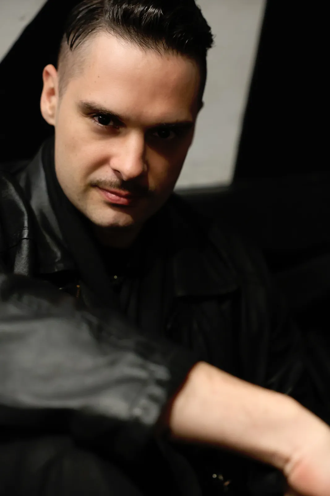 Moody low-light portrait of a man in a black leather jacket