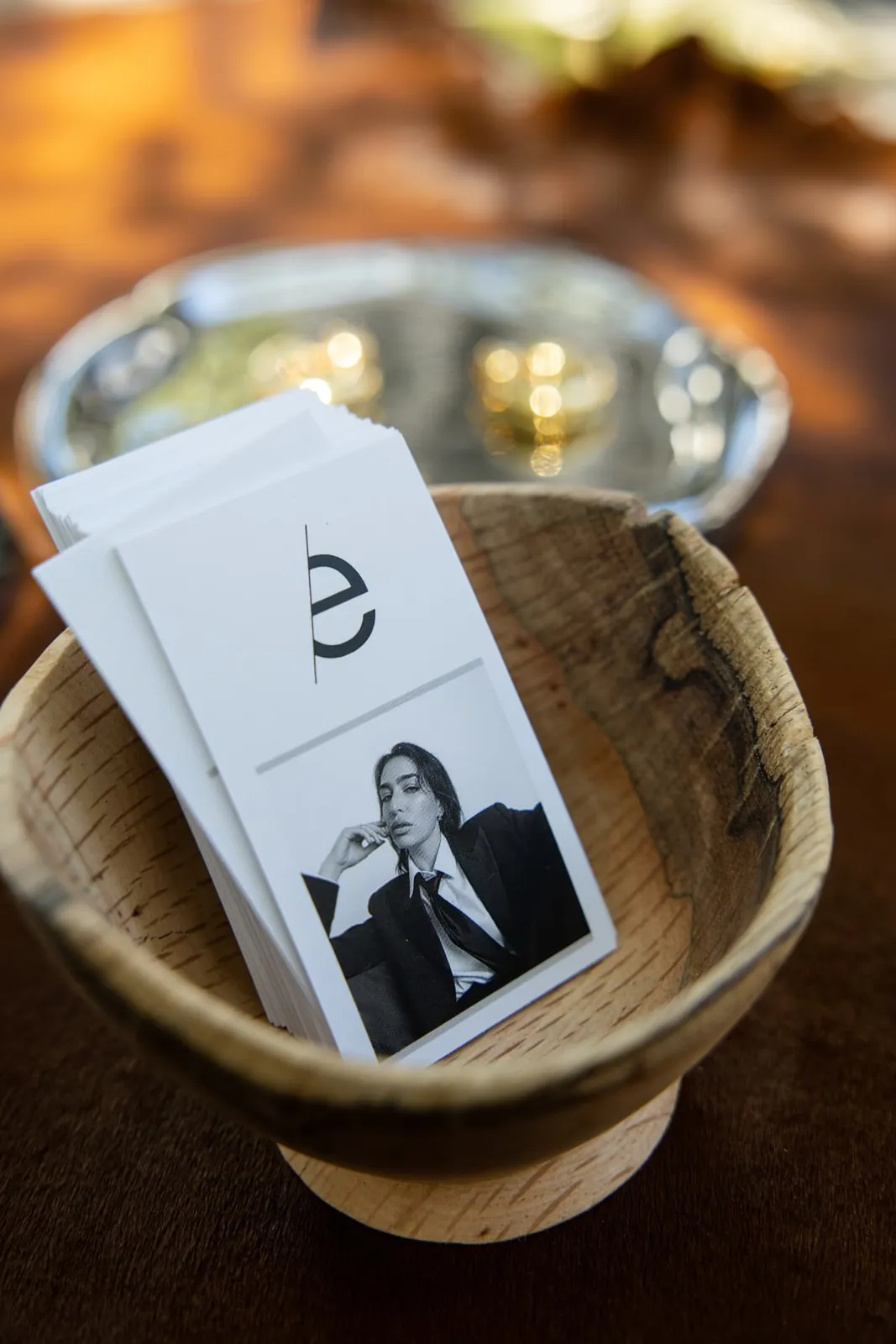 Editorial business cards stacked in a wooden bowl on a warm-lit table