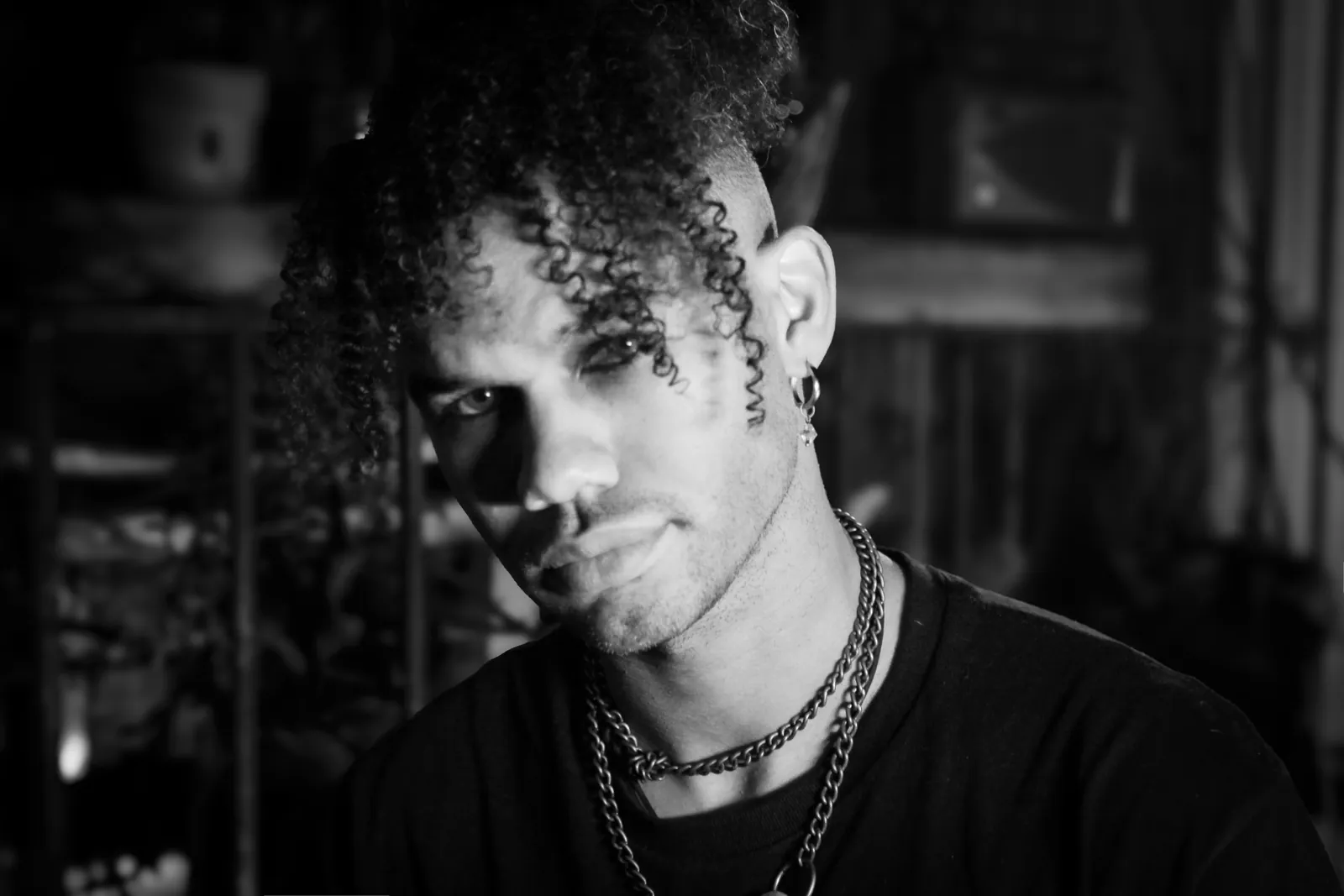 Black-and-white portrait of a person with curly hair and layered necklaces