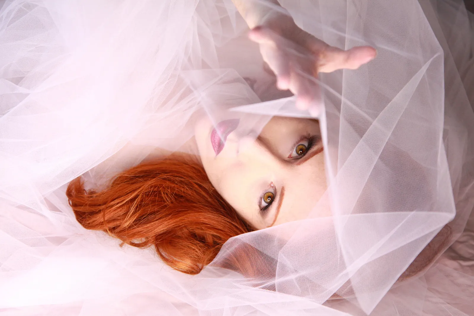 Red-haired model wrapped in soft pink tulle